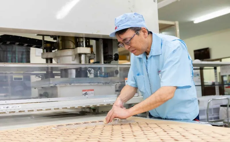 工人拿起加工过的产品和冲压加工机的照片