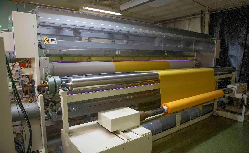Photo of a corona treatment machine processing yellow mesh