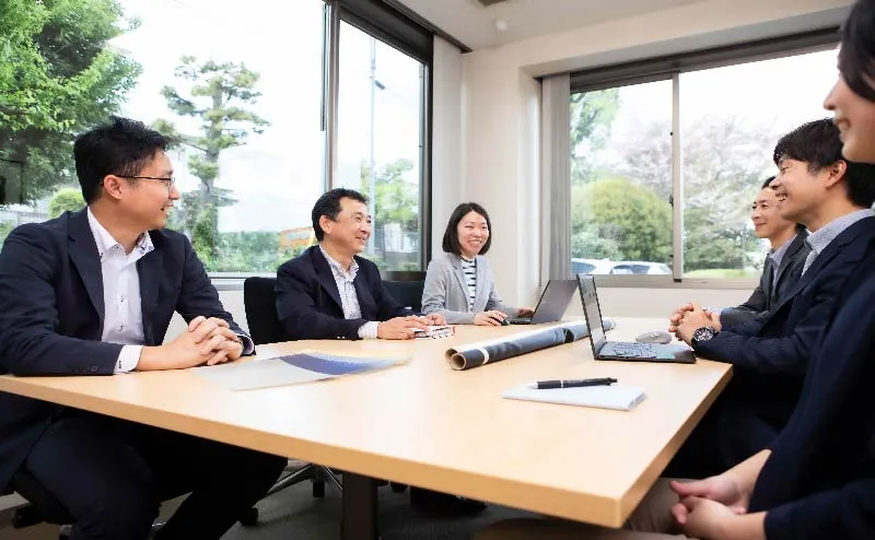 ビジネスマンが会議室で打ち合わせをしている様子。