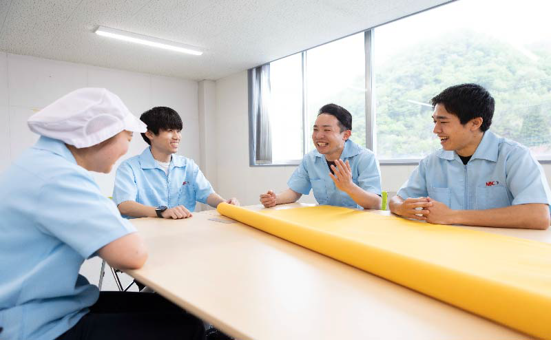 会議室で黄色のスクリーン印刷用メッシュを前に話し合う作業員